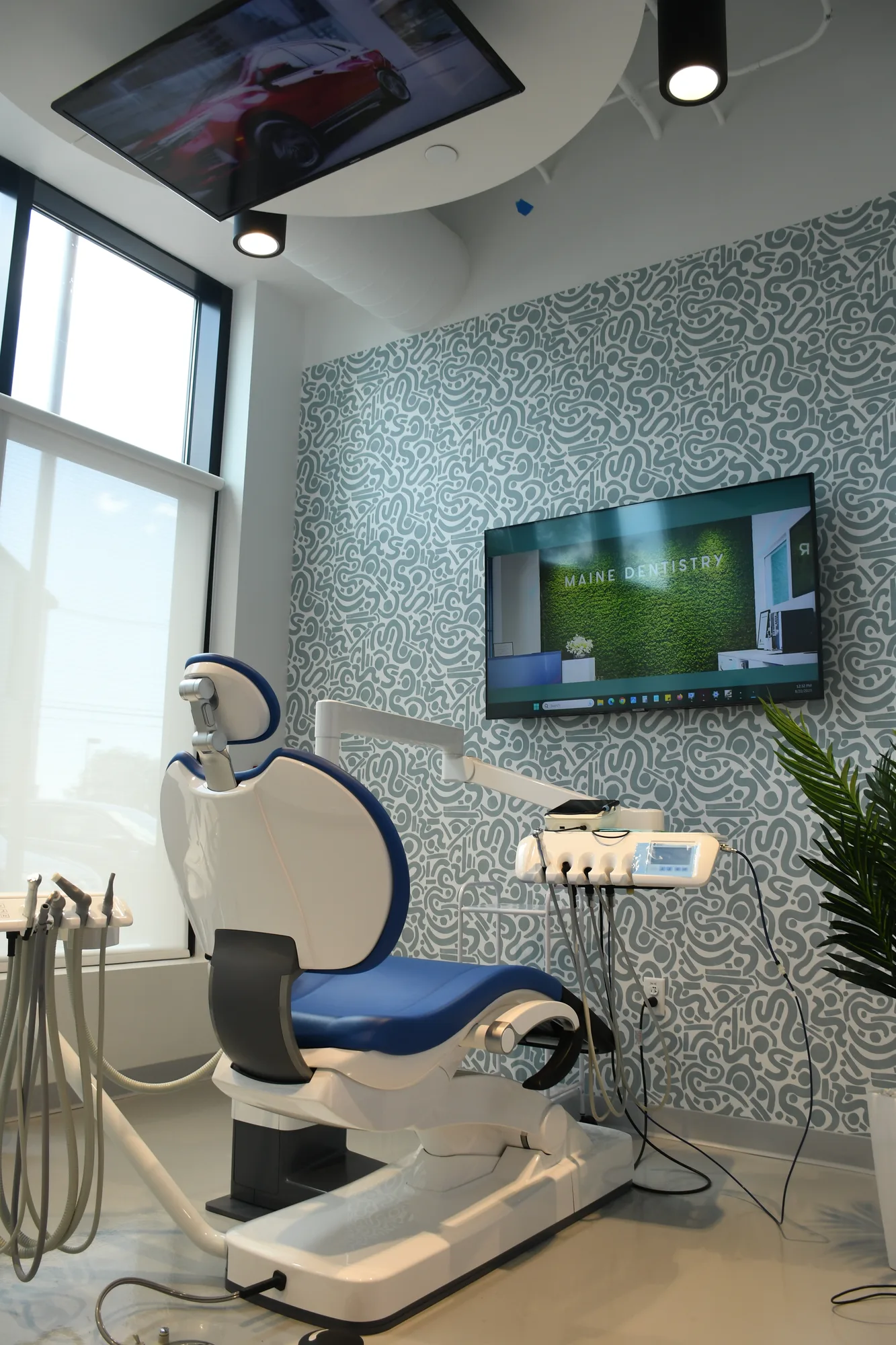 A Maine Dentistry treatment room with a patterned wall, screens, and a blue dental chair
