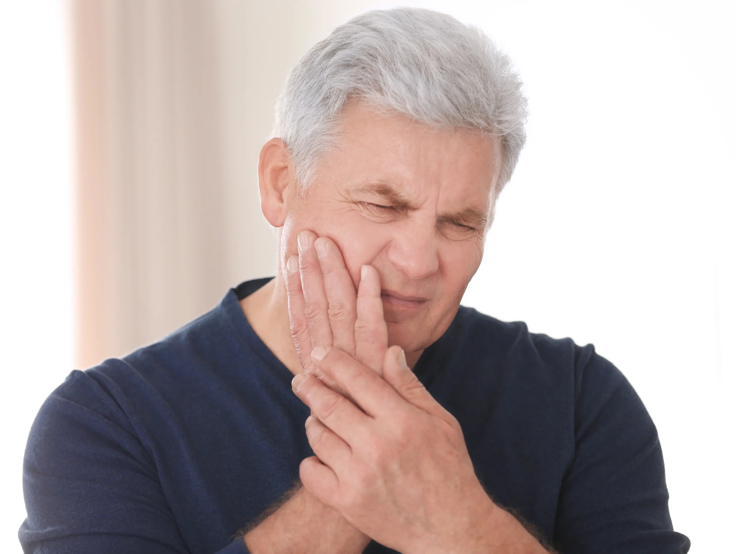 Person touching their cheek while experiencing discomfort