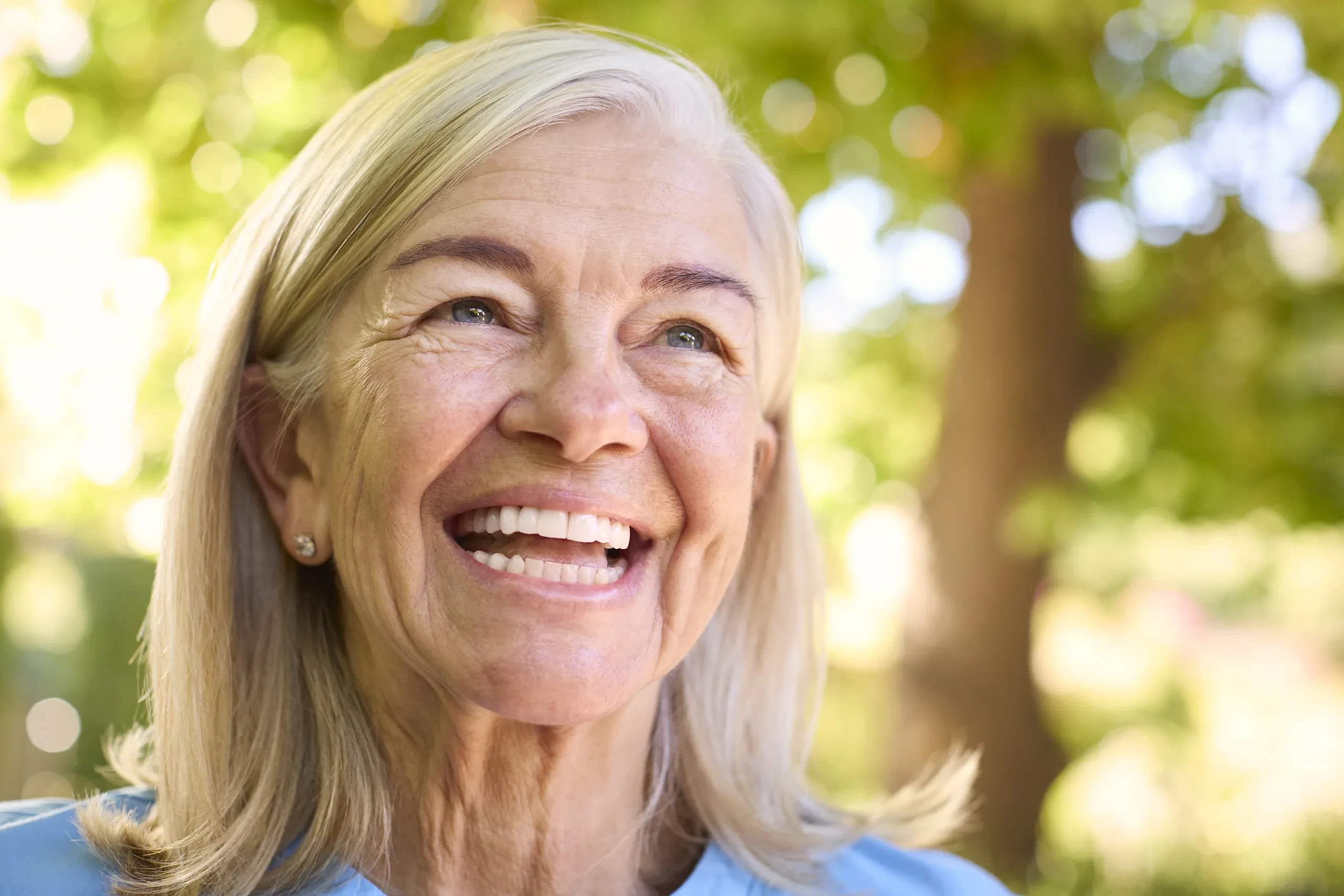 Naturally smiling woman outdoors in warm sunlight, looking to the right