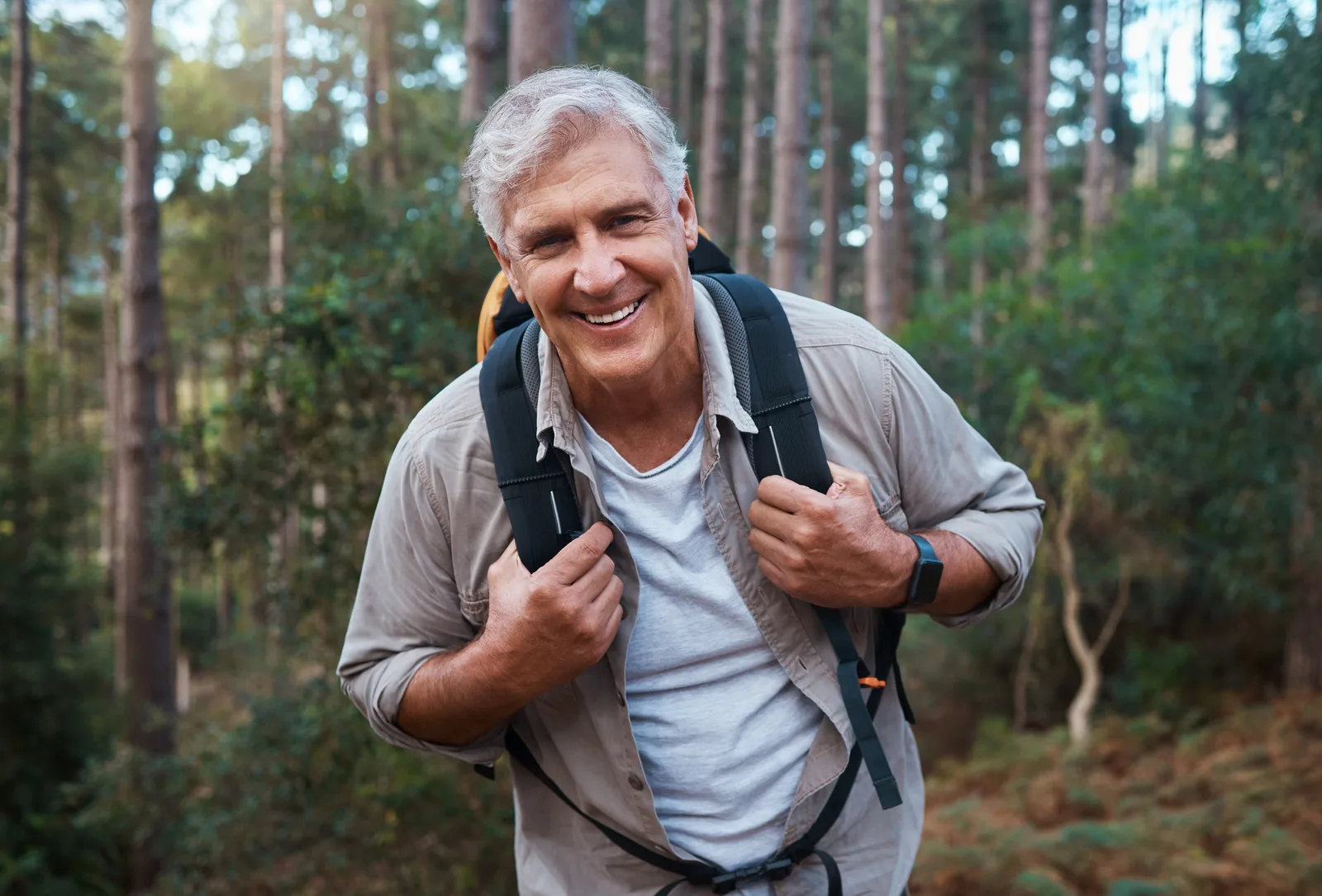 Smiling man hiking along a wooded trail